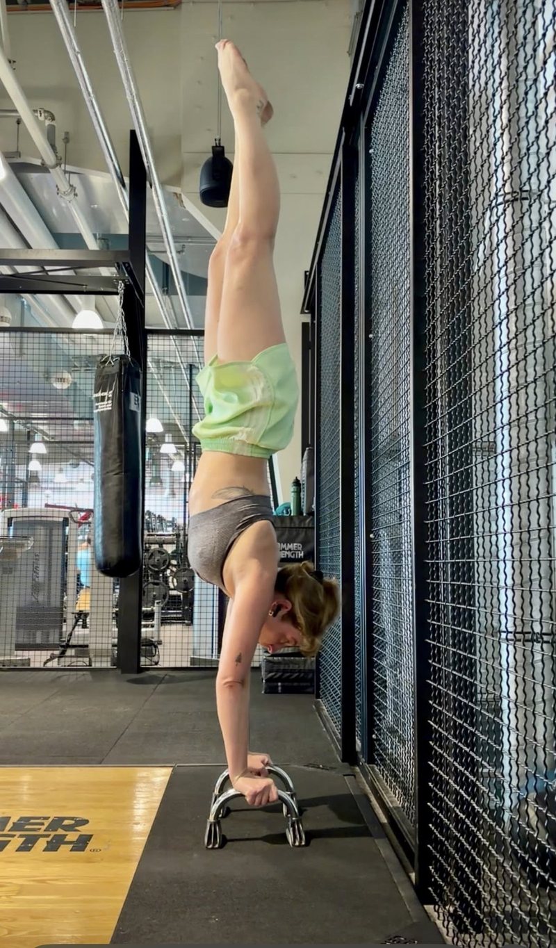 Freier Handstand auf Parallettes, gestreckte Linie von den Händen bis zu den Fußspitzen